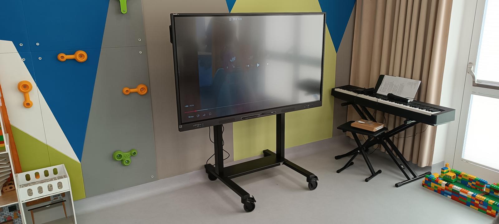 Monitor na stojaku z kółkami w sali przedszkola w Gdańsku